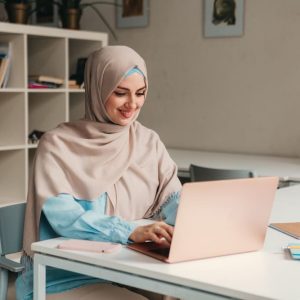 Adult Muslim woman learning Egyptian Arabic online from home using a laptop during a live virtual Egyptian Arabic course.