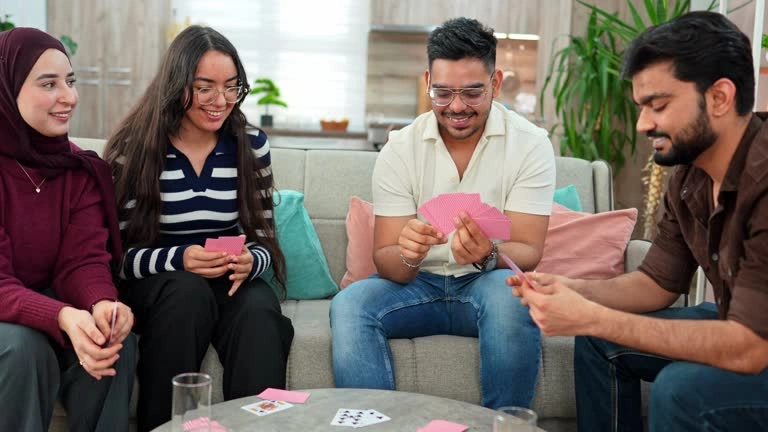 Group of friends laughing while playing cards together at home