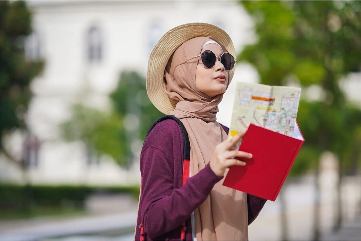 Why Learn Arabic? Woman in hijab and sunhat reading a city map while traveling